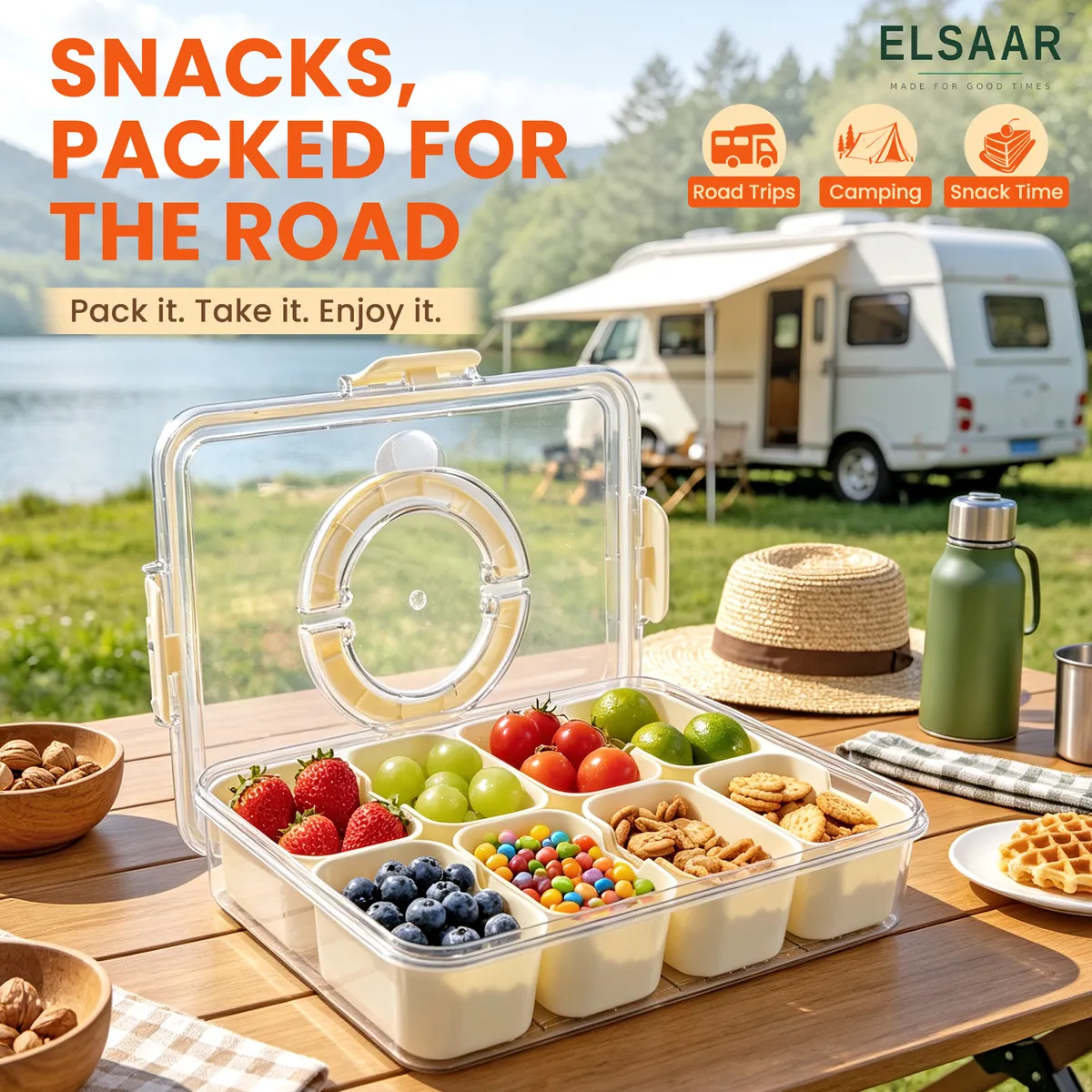 Snackle Box on a camping table by a lake, next to a camper van
